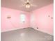 Pink bedroom featuring a ceiling fan, neutral flooring, and a sunlit window at 553 Georgia Ave, Statesville, NC 28677