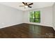 Bright bedroom featuring hardwood floors, ceiling fan, and a large window with views of the outside greenery at 7378 Winery Ln, Charlotte, NC 28227