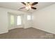An empty bedroom showcases a neutral color palette, ceiling fan, bay window, and carpeted floors at 1125 Kurt Ct, Charlotte, NC 28209