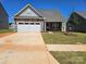 Charming single-story home featuring a stone facade, a two-car garage, and a well-manicured lawn at 126 Brixham Loop, Troutman, NC 28166