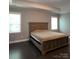 Serene bedroom with tray ceiling, dark wood floors, neutral walls, and abundant natural light from large windows at 2044 Sweet William Dr, Harrisburg, NC 28075