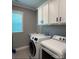 This laundry room has white cabinets and machines and one bright window at 2044 Sweet William Dr, Harrisburg, NC 28075