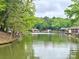 A scenic lake view showcasing calm waters with docks and a boat, surrounded by lush greenery at 416 Plantation Way, Mount Gilead, NC 27306