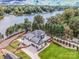 Stunning aerial view of a modern farmhouse situated on a waterfront property, surrounded by lush trees at 110 Emmaline Ct, Troutman, NC 28166