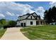 Side view of a modern farmhouse with a spacious driveway and well-maintained lawn leading to the garage at 110 Emmaline Ct, Troutman, NC 28166