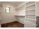 Walk-in closet with white shelves, wood flooring, and a window at 116 Emmaline Ct, Troutman, NC 28166
