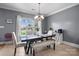 Inviting dining area featuring a chandelier, bench seating, and large windows that bring in natural light at 104 Castle Pines Ln, Statesville, NC 28625