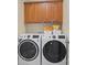 Well-equipped laundry room featuring a GE washer and dryer, complemented by wood cabinets at 104 Castle Pines Ln, Statesville, NC 28625