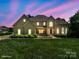 Stately home with manicured lawn and garden beds against a vibrant twilight sky at 122 Long Cove Ln, Mooresville, NC 28117