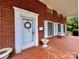 Inviting front porch with red brick exterior and white door at 1506 Dallas Cherryville Hwy, Dallas, NC 28034