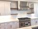 Well-lit kitchen featuring white cabinets, stone countertops, stainless steel appliances, and floating wooden shelves at 13217 Terrace Court Dr, Charlotte, NC 28278