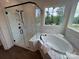 Bright bathroom features a soaking tub, glass enclosed shower, white tile and wood look flooring at 2027 Cedar Falls Dr # 75, Waxhaw, NC 28173