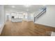 Open concept living room with a kitchen, staircase, hardwood floors, and white trim at 2027 Cedar Falls Dr # 75, Waxhaw, NC 28173