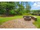Paver patio with a stone fire pit surrounded by lush greenery in a fenced yard at 2027 Cedar Falls Dr # 75, Waxhaw, NC 28173