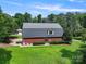 Back view of a brick home with a metal roof and surrounded by lush greenery at 6620 Old Concord Rd, Salisbury, NC 28146