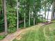 Wooded backyard with lake access, walkway, and seating area at 4409 Solemn Point Ln, Charlotte, NC 28216