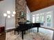 Living room features a grand piano, stone fireplace, and vaulted ceiling at 4409 Solemn Point Ln, Charlotte, NC 28216