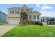 Inviting two-story home with a covered porch, manicured lawn, stone accents, and attached two-car garage at 135 Tenth Green Ct, Statesville, NC 28677