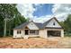 Under-construction brick home with a spacious attached garage, black roof, and covered front porch, set in a wooded area at 1500 Crowders Creek Rd, Gastonia, NC 28052