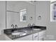 Modern bathroom showcasing a granite countertop with dual sinks, black fixtures, and a shower with natural light at 6201 Long Branch Rd, Salisbury, NC 28147