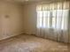 Sunlit bedroom with neutral walls and flooring complemented by large windows dressed in sheer curtains at 2310 Montford Nw Ave, Concord, NC 28027