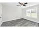 A neutral bedroom features gray tone wood flooring, a window and a ceiling fan at 6217 Long Branch Rd, Salisbury, NC 28147