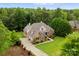 Aerial view of a lovely two-story brick home with a manicured lawn, driveway, and surrounded by mature trees at 160 Northington Woods Dr, Mooresville, NC 28117