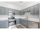 Well-lit kitchen with stainless steel appliances, grey cabinets, mosaic backsplash, and white countertops at 12229 Savannah Garden Dr, Charlotte, NC 28273