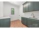 Laundry room with stylish brick floors, green cabinetry, quartz countertops, and modern fixtures at 626 Concord Rd, Davidson, NC 28036