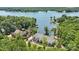 Aerial view of an exquisite lakeside property surrounded by mature trees and lush greenery at 18304 Rosapenny Rd, Charlotte, NC 28278