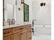 Elegant bathroom featuring a soaking tub, a stylish vanity, contemporary fixtures, and tasteful marble accents throughout at 18304 Rosapenny Rd, Charlotte, NC 28278
