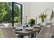 Dining room boasts modern table setting for eight and view to the beautifully wooded outdoors at 18304 Rosapenny Rd, Charlotte, NC 28278
