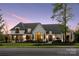 Elegant home with lush landscaping, large windows, a porte cochere, and a serene twilight sky at 18304 Rosapenny Rd, Charlotte, NC 28278