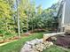 Landscaped backyard featuring a stone path, lush lawn, and surrounding mature trees at 859 Tamary Way # 34, Landis, NC 28088