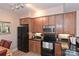 Modern kitchen with dark wood cabinets, granite countertops, and black appliances at 1320 Fillmore Ave # 311, Charlotte, NC 28203