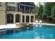 Inviting pool area featuring a rock hot tub, covered patio, and manicured lawn for luxurious outdoor living and relaxation at 7582 Cottonwood Dr # 39, Denver, NC 28037