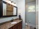Bathroom with a granite countertop, dark wood cabinets, and shower with stone tile surround at 7582 Cottonwood Dr # 39, Denver, NC 28037