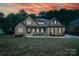Charming stone and stucco home with a manicured lawn with warm interior lighting at sunset at 7582 Cottonwood Dr # 39, Denver, NC 28037
