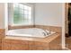 A relaxing soaking tub is surrounded by tile and a window allowing natural light into the bathroom at 2518 Wellesbourne Ln, Sherrills Ford, NC 28673