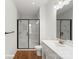 Bright bathroom features a glass shower with dark trim, wood-look floors, and white vanity at 5830 Pittmon Ln, Kannapolis, NC 28081