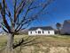 A single-story house featuring a gable roof stands on a lush lawn, framed by the silhouette of a grand tree at 9609 Stokes Ferry Rd, Gold Hill, NC 28071