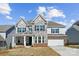 Beautiful two-story home showcasing stone facade, blue shutters, and a well-manicured lawn under a bright sky at 121 Clawton Loop, Mooresville, NC 28115