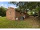 Rear exterior of a brick home featuring a red roof, a grassy yard, and mature trees at 3338 Passmore Rd, Rock Hill, SC 29730