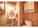 Cozy half bathroom featuring a pedestal sink, brick wallpaper, and white toilet at 3814 Watson Church Rd, Monroe, NC 28110