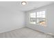 A bright bedroom with neutral carpet and view of a neighboring home through a large window at 4684 Hopsack Dr # Cal0105, Indian Trail, NC 28079