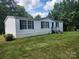 White single-story house with blue shutters and trim, set on a green lawn with mature trees in the background at 6261 Burnhurst Ln, Denver, NC 28037
