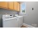 Bright laundry room featuring a washer, dryer, and overhead cabinets at 8516 Mcilwaine Rd, Huntersville, NC 28078