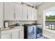Modern laundry room with front loading washer and dryer, built-in sink, and cabinet storage at 127 Tradition Ln, Mooresville, NC 28115