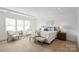 Light-filled main bedroom with a queen size bed, a cushioned bench, side tables, sitting chairs and natural wood floors at 5225 Glenwalk Dr # 0061, Charlotte, NC 28269