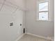 A functional laundry room with a window, wire shelving, and hookups for a washer and dryer at 4808 Glen Stripe Dr # Cal0036, Indian Trail, NC 28079